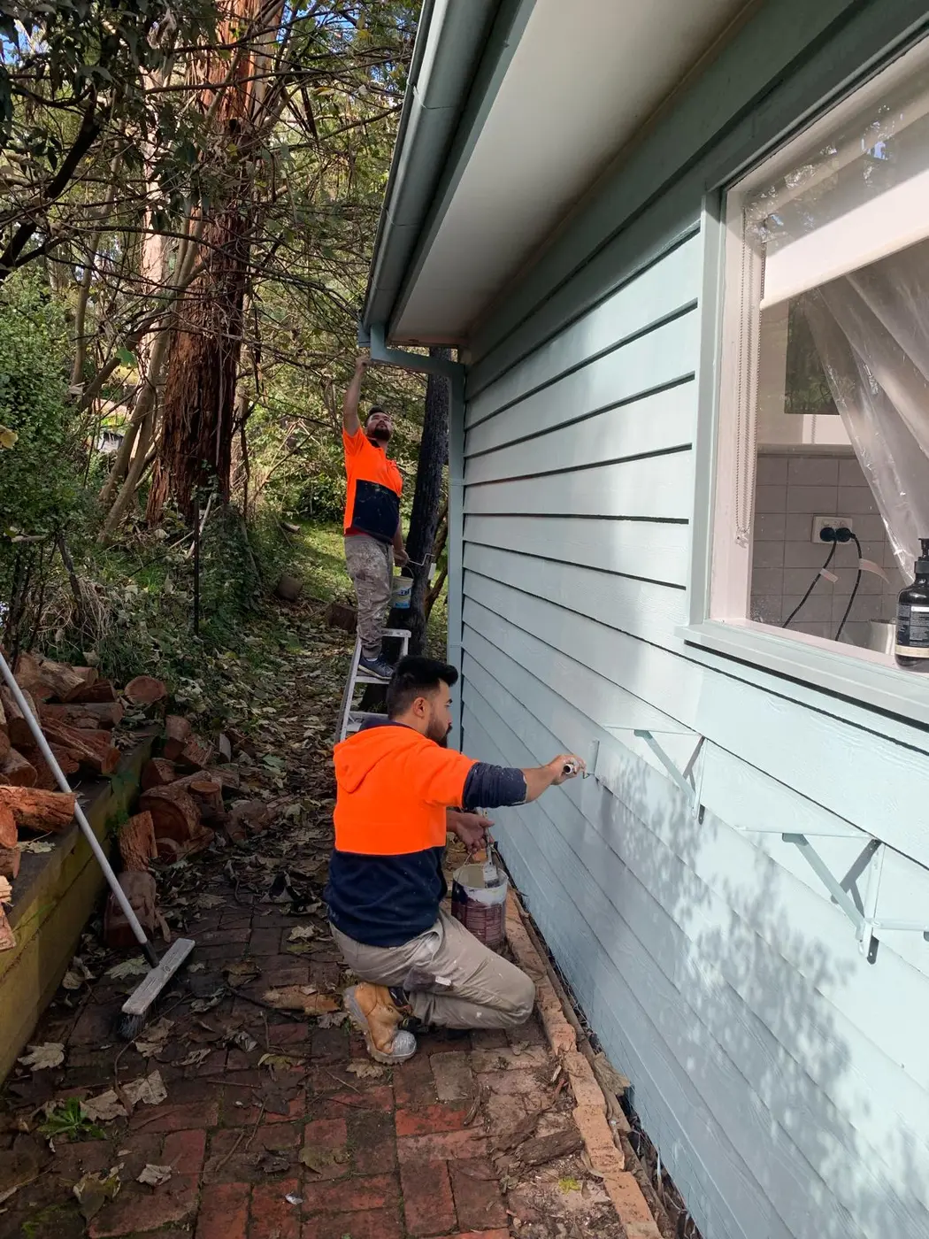 Painter finishing a weatherboard exterior